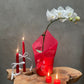 Decorative setup with red candles and a white orchid on a wooden surface against a gray background