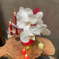 White orchid on a wooden surface with red candles in the background